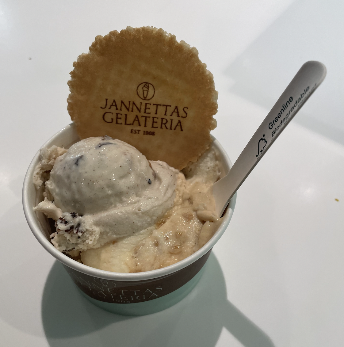 Two scoops of ice cream, one Christmas pudding flavour and another spiced apple, in a tub with a wafer that says "Jannettas Gelateria", a famous place for gelato in St Andrews, Scotland.
